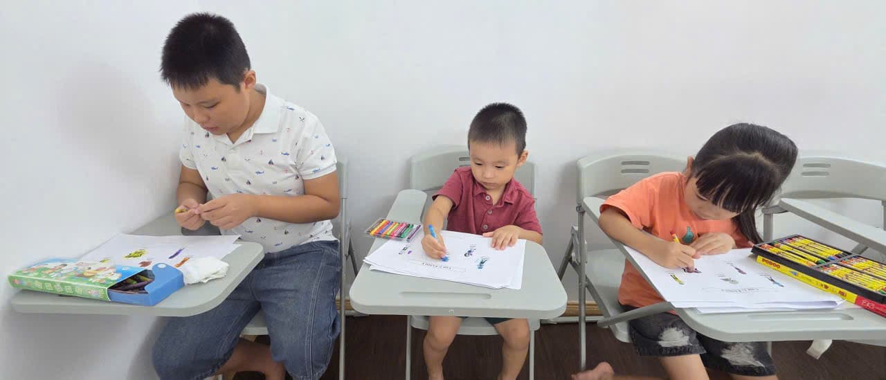 Ba bạn nhỏ tô màu phiếu bài tập tiếng Anh tại lớp